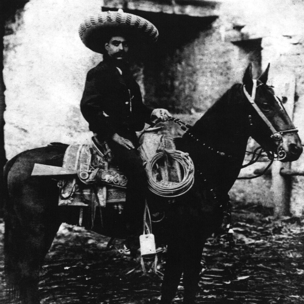 A black and white photograph of a man sitting on a horse.